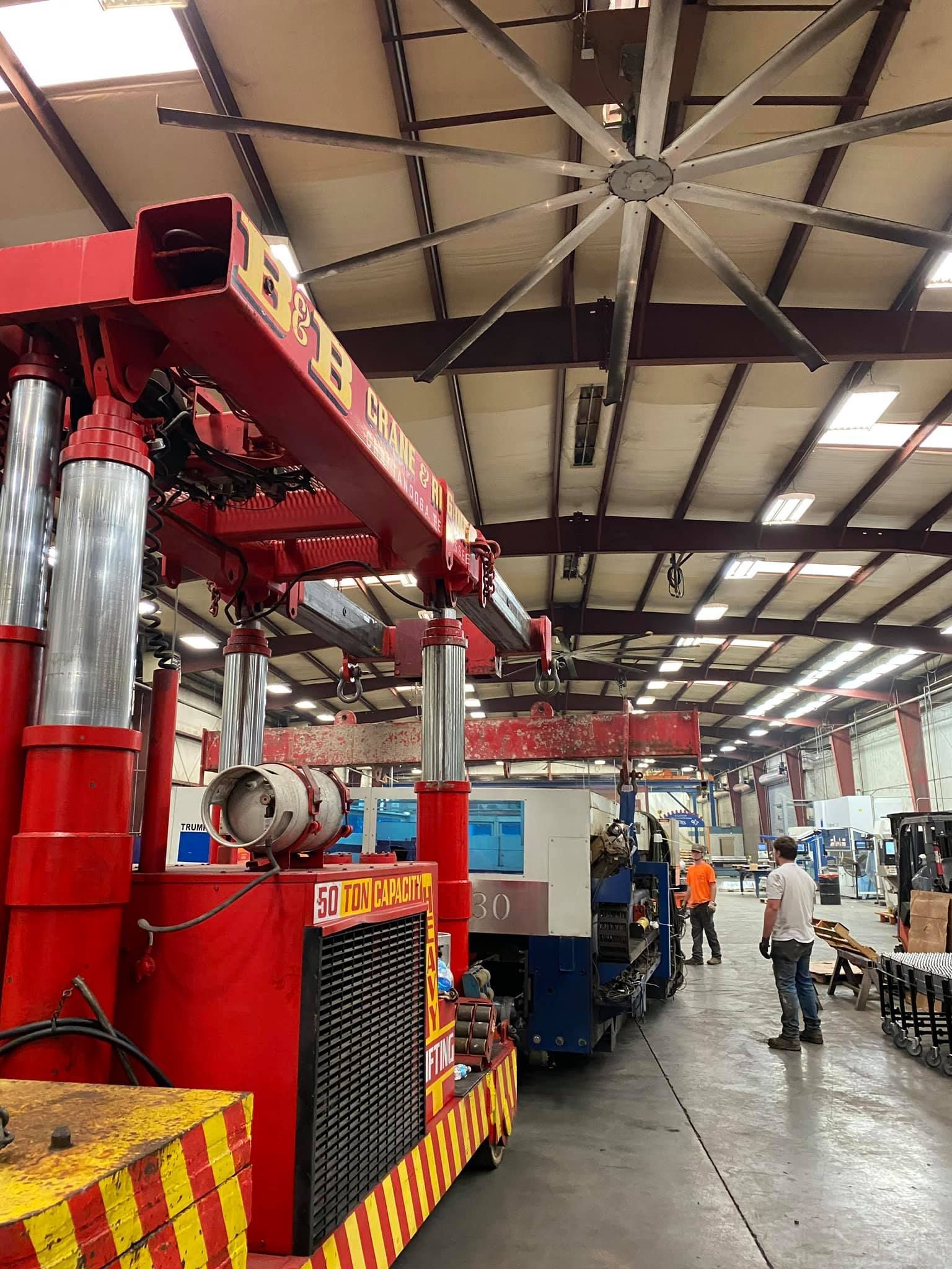 A large ceiling fan is hanging from the ceiling of a factory.