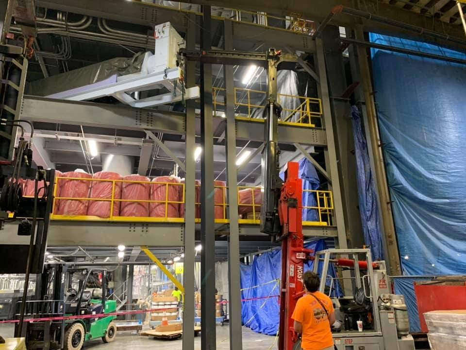 A man is standing next to a forklift in a warehouse.