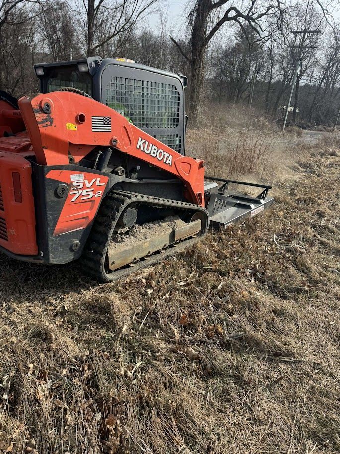 Orange Kubota SVL75-2 compact track loader mowing dry grass in a field.