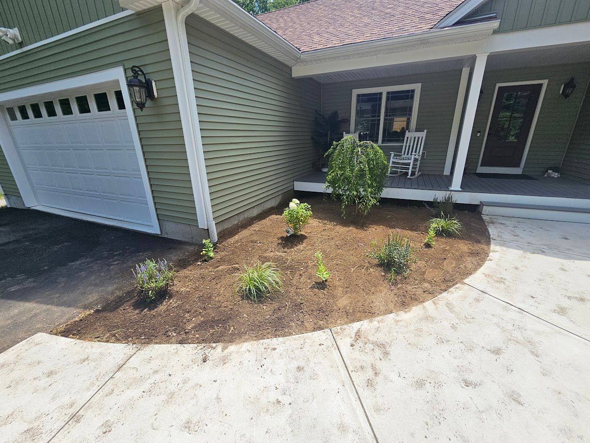 Green house with newly mulched flower bed and concrete walkway.