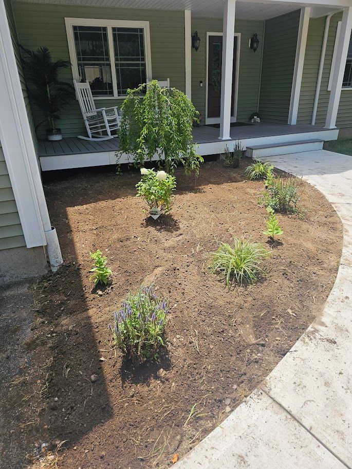 Newly planted garden bed with green house in background.