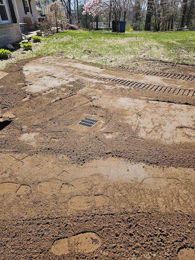 Dirt yard with tire tracks and a drainage grate.