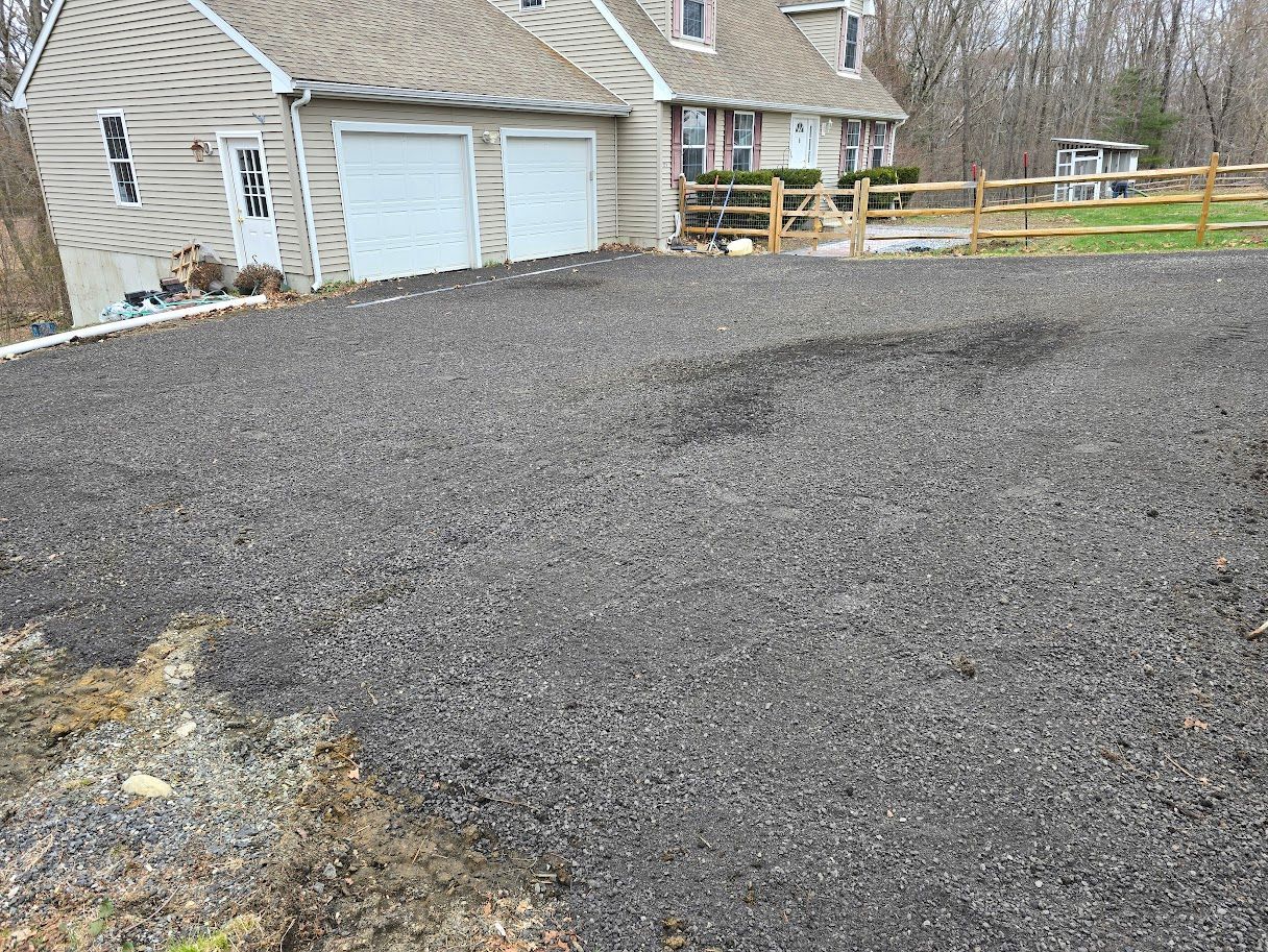 Driveway with fresh black asphalt in front of a house with a two-car garage.