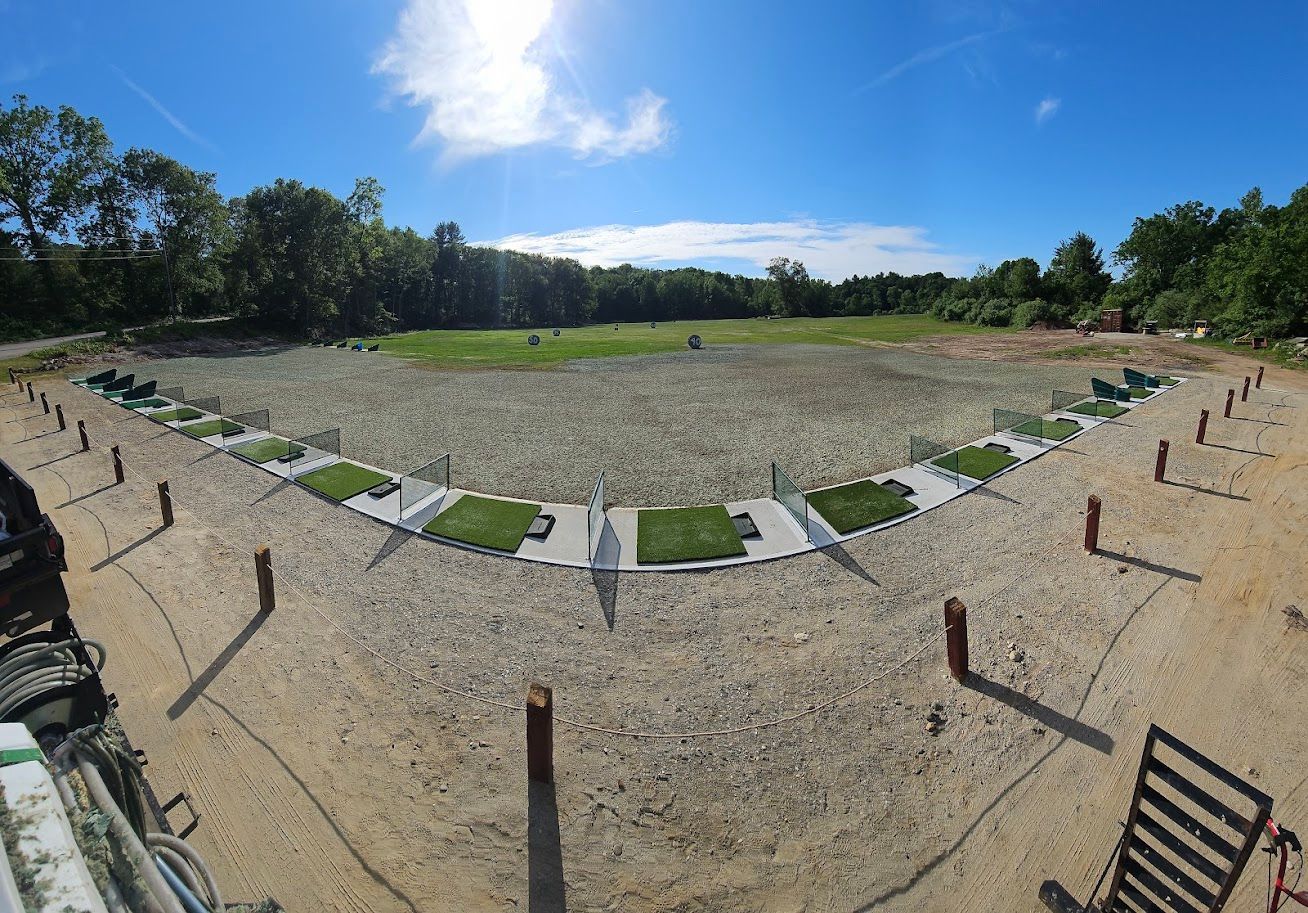A wide-angle view of an outdoor archery range featuring multiple shooting stations along a curved, gravel-covered area