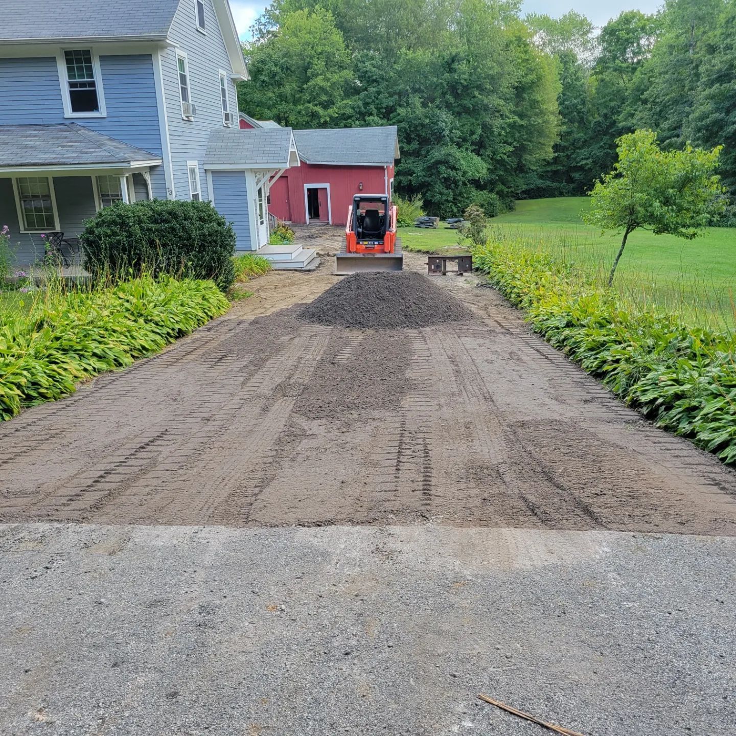 a bulldozer is moving dirt in a driveway in front of a house