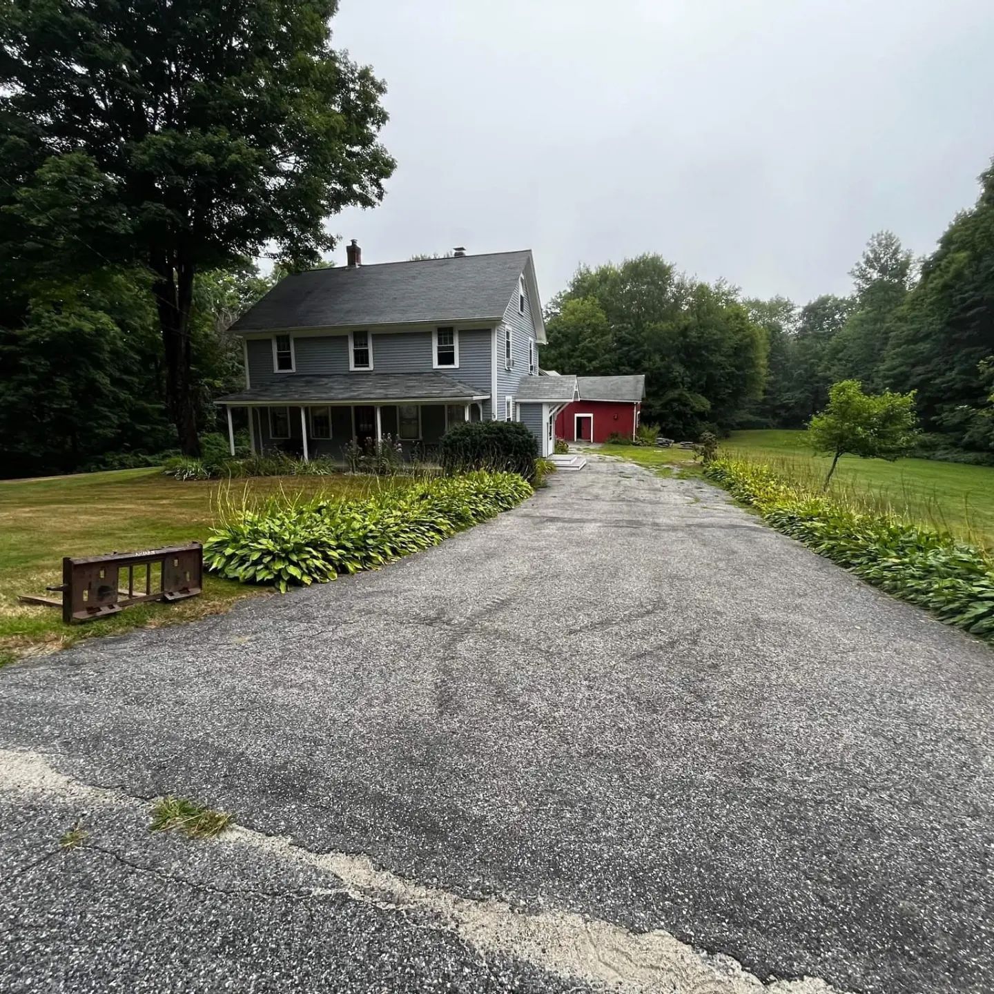 a driveway leading to a house with a red barn