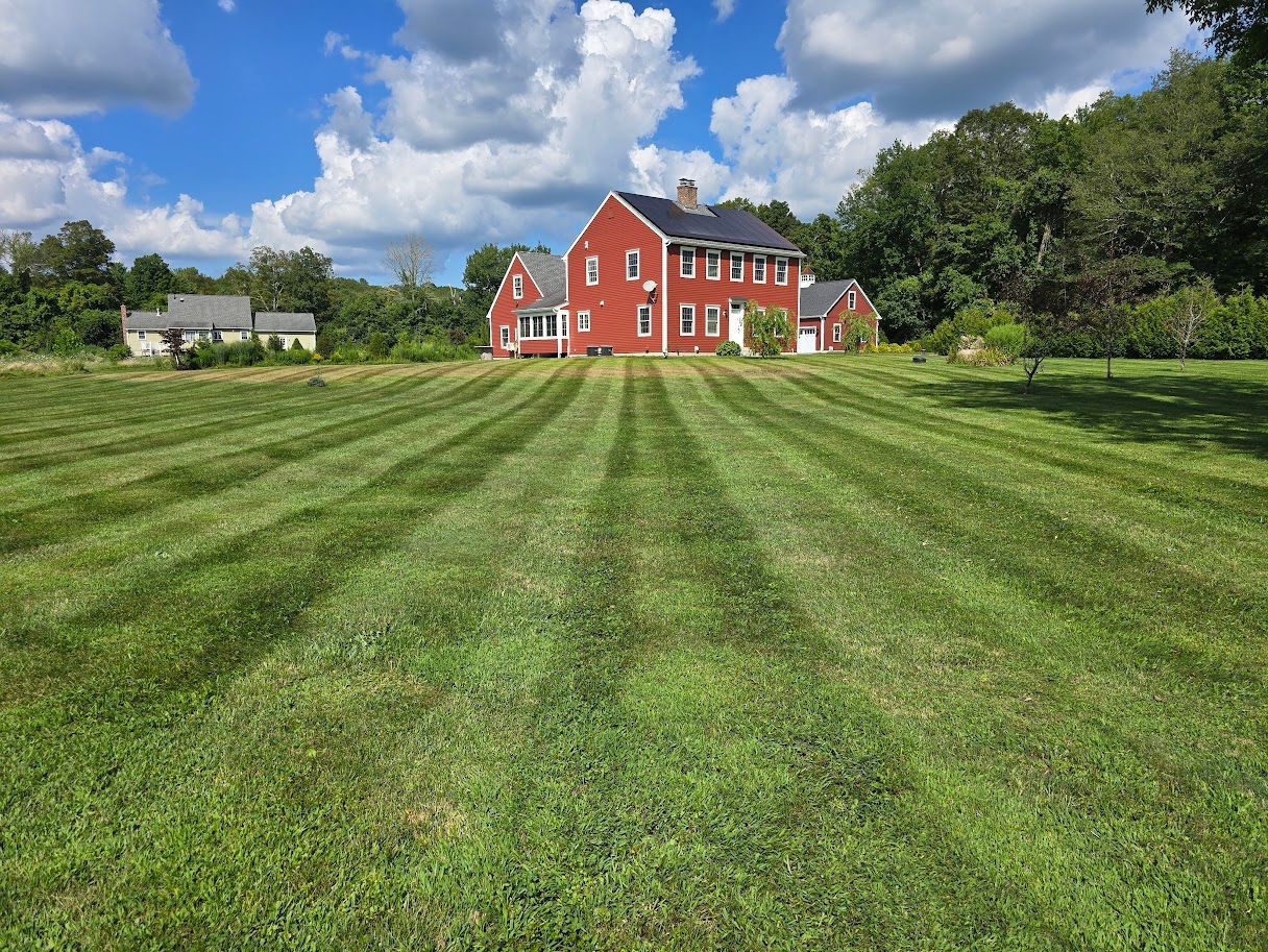Red house with striped lawn on a sunny day.