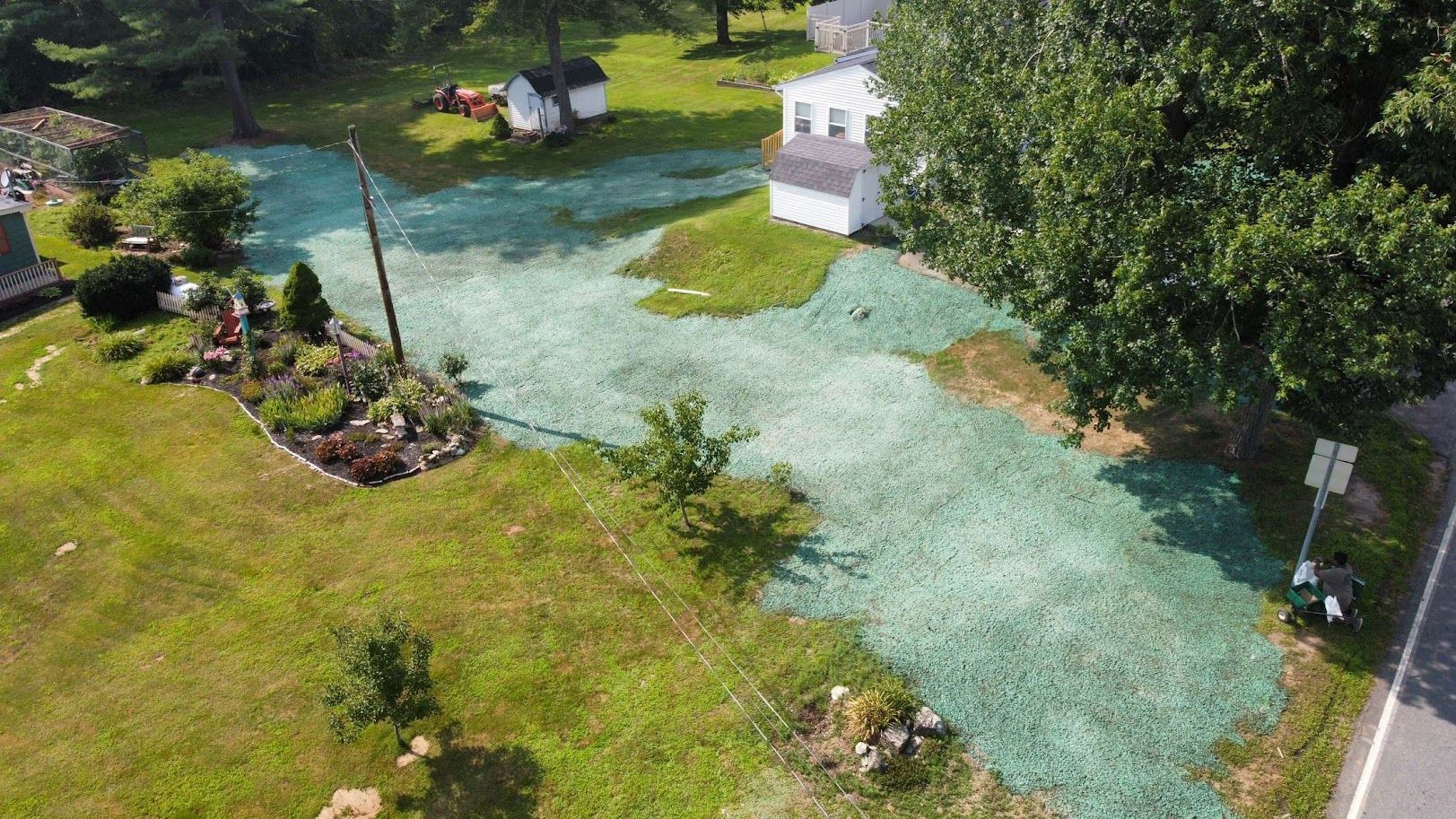 An aerial view of a yard featuring a patch of ground recently treated with bright green hydroseed mulch