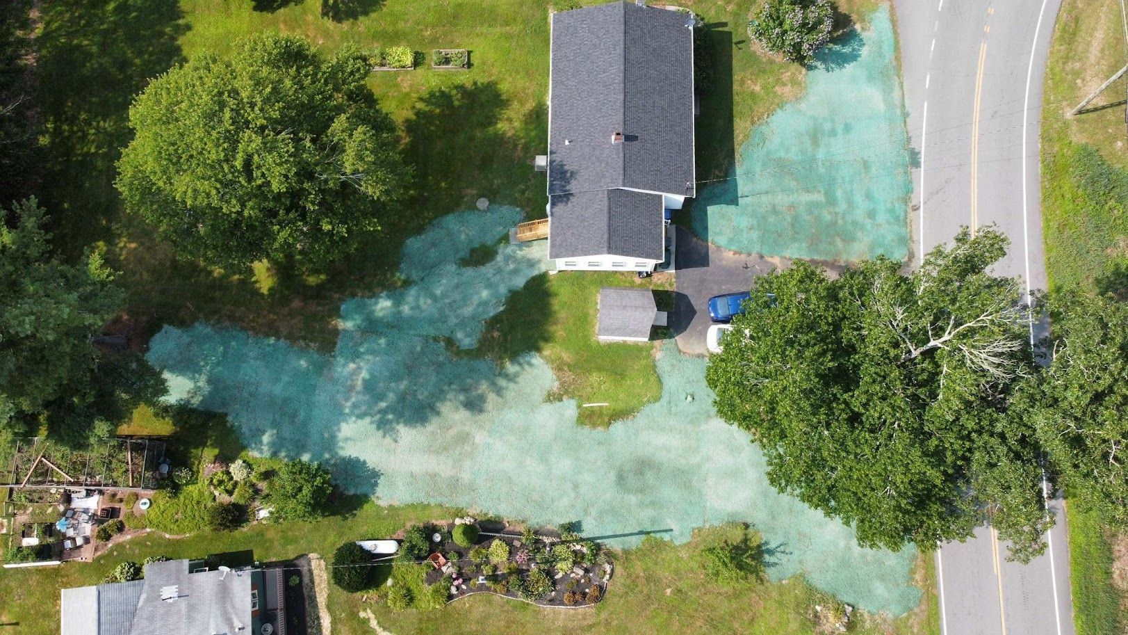 Aerial view of a house with patches of green hydroseed mulch applied to the surrounding lawn and driveway area