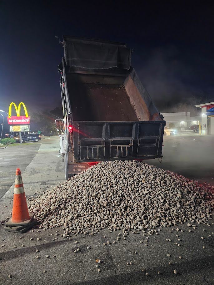 A dump truck unloading a large pile of potatoes in a parking lot at night