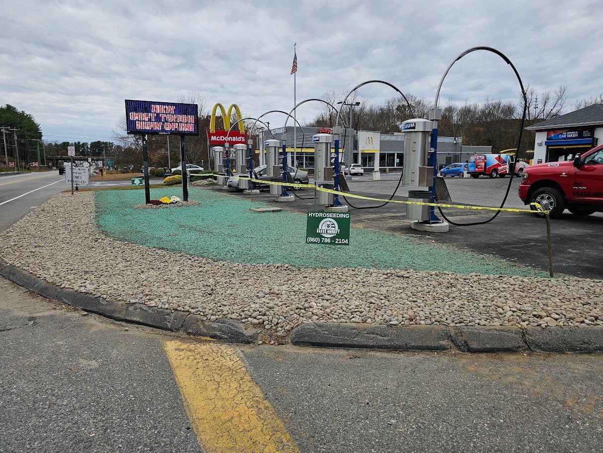 A row of vacuum stations stands in a gravel lot with a green landscaped bed