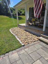 A front porch with a rock garden, brick trim, and an American flag.
