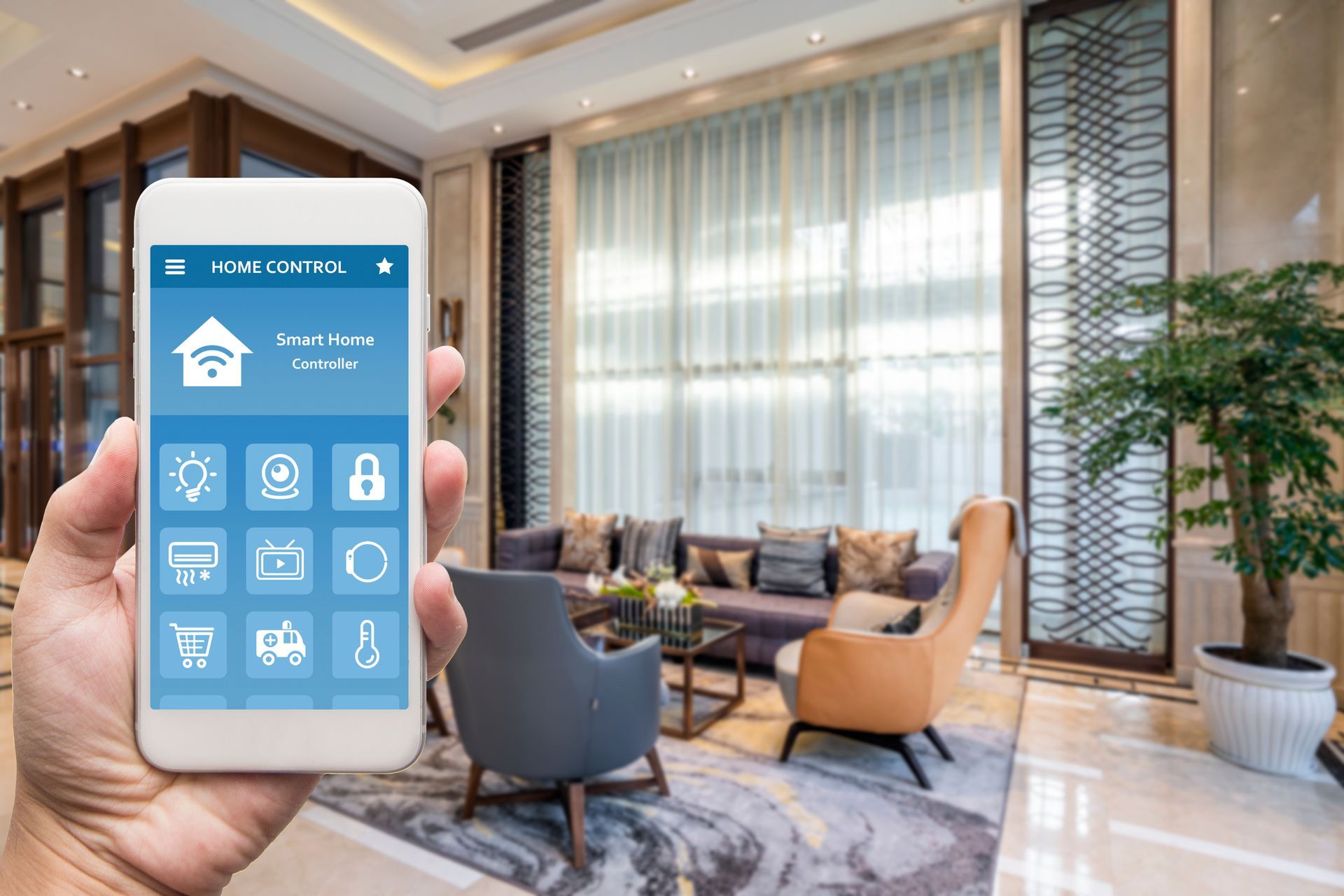 Hand holding a phone displaying a smart home interface; living room interior in the background.