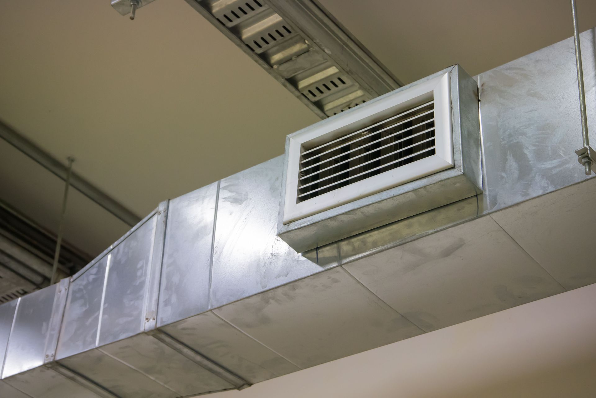 Silver air duct system with a rectangular vent on a ceiling.