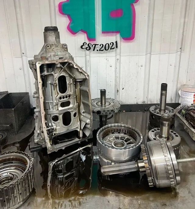 Disassembled car transmission parts on a workbench in a mechanic shop with logo reading "Superior Transmissions & Auto."