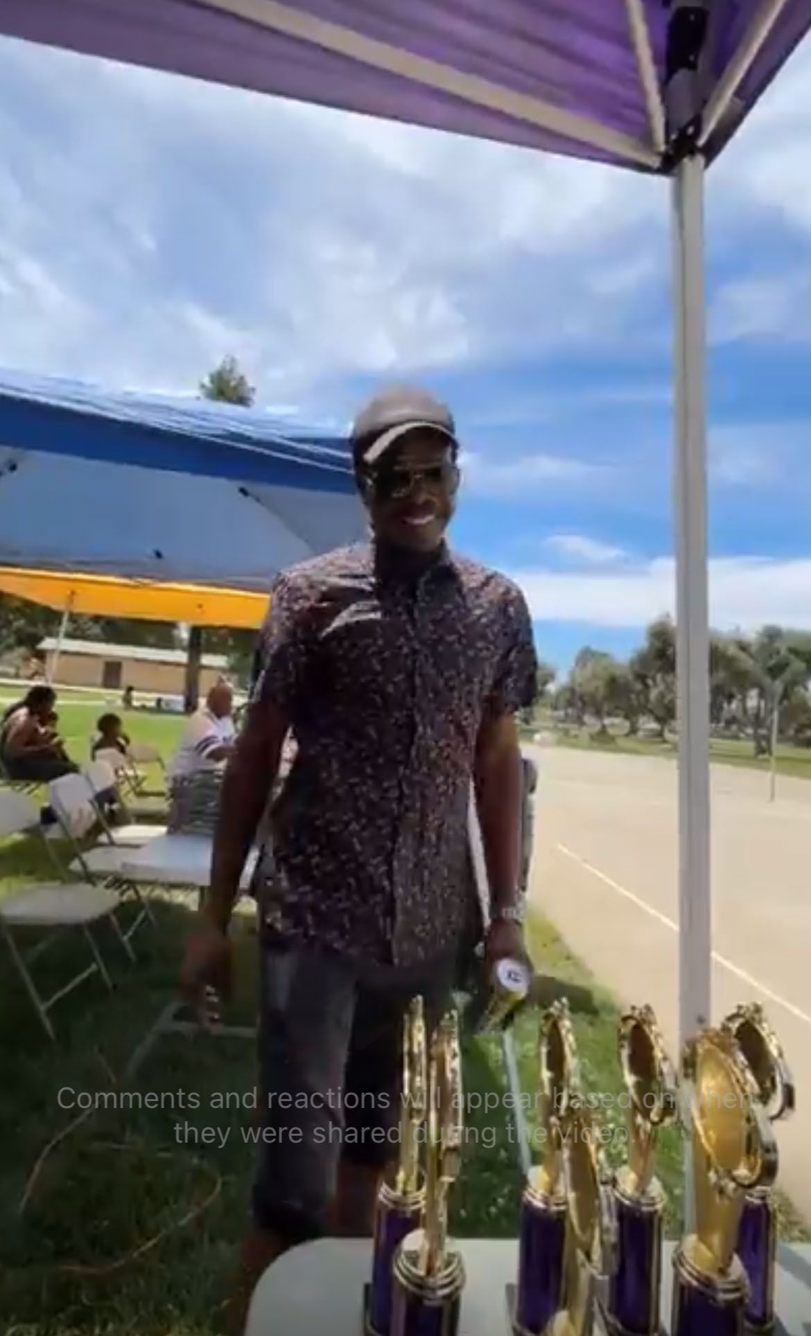 A man is standing in front of a table with trophies on it.