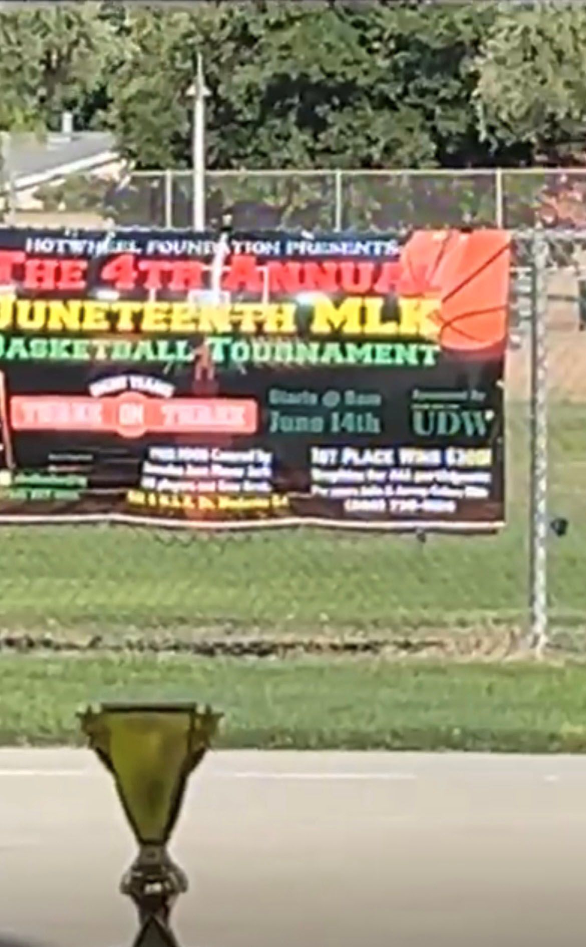 A trophy is sitting in front of a sign that says the 4th annual Juneteenth MLK basketball tournament
