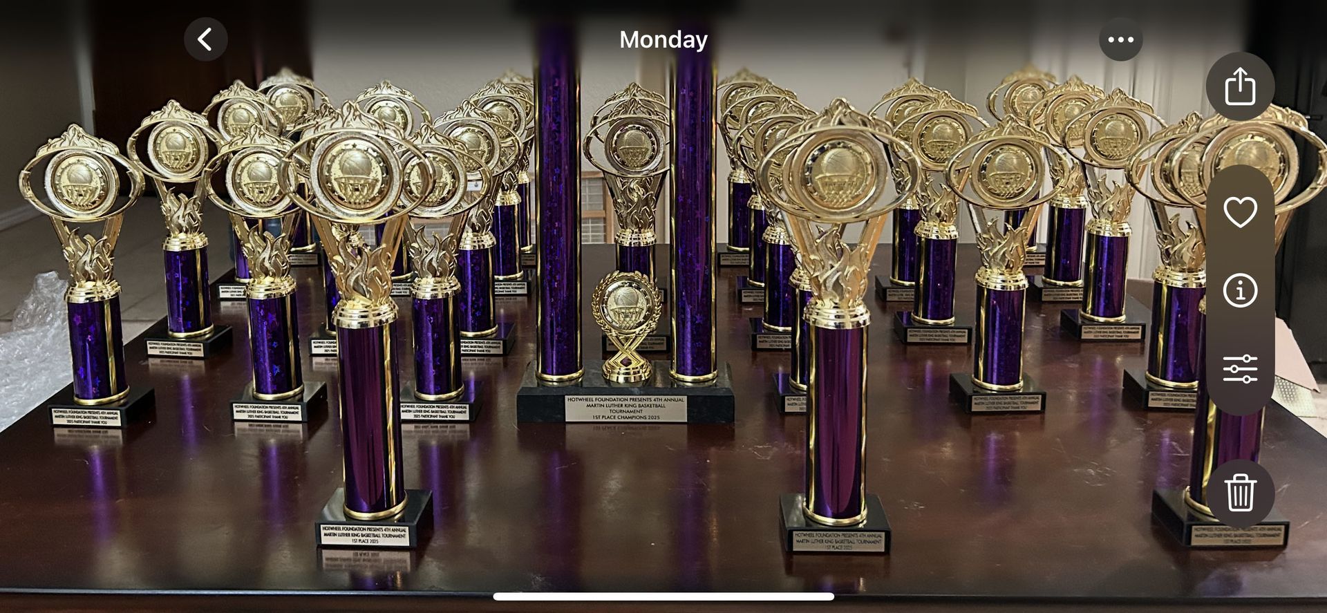 A bunch of trophies are sitting on a wooden table.