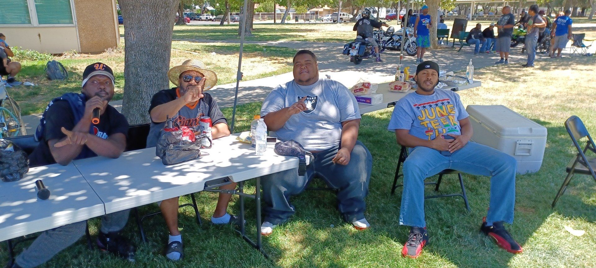 four men watching basketball underneath a treee