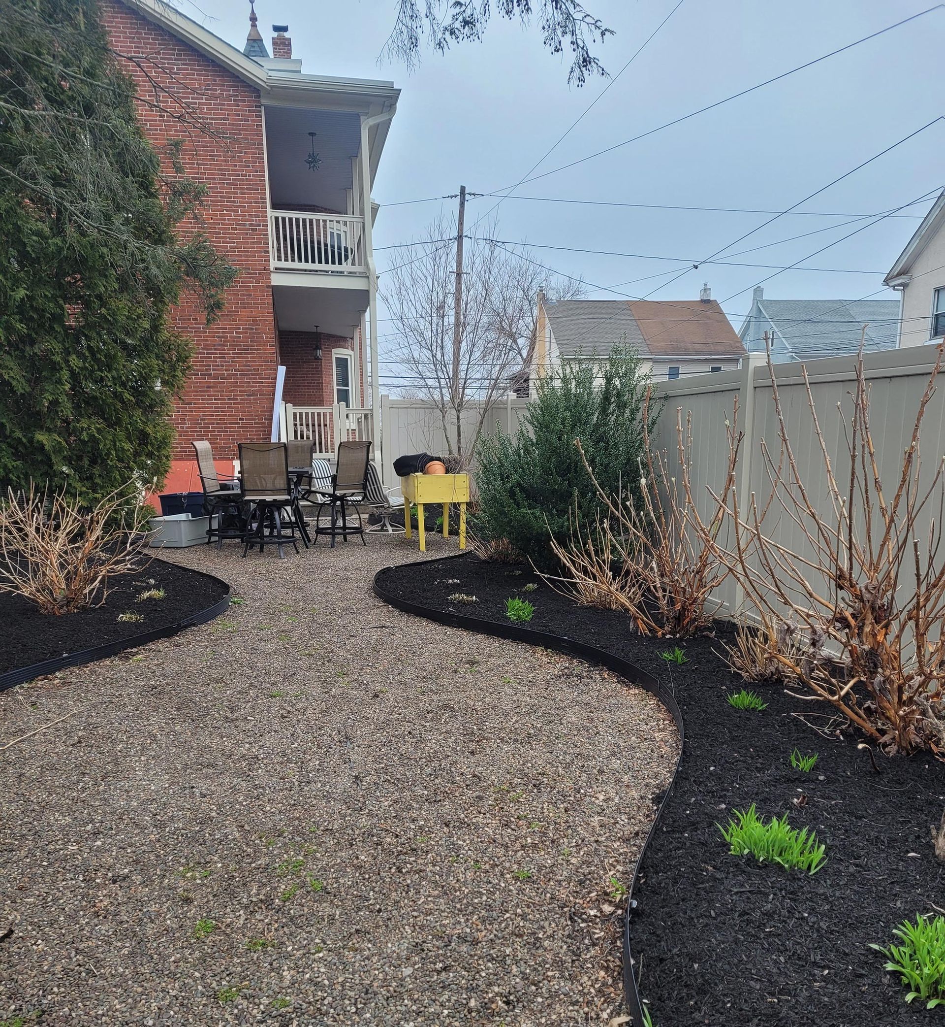 A backyard with a brick house and a fence surrounding it