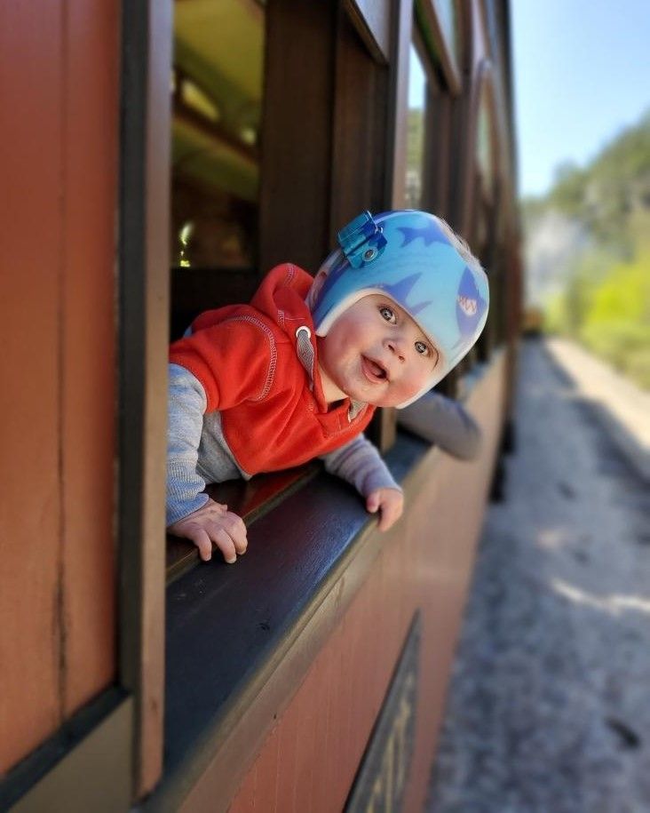 A baby is looking out of a train window