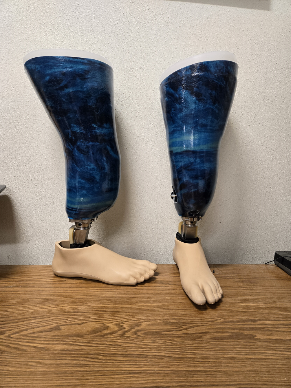 A pair of prosthetic legs and feet are sitting on a wooden table.