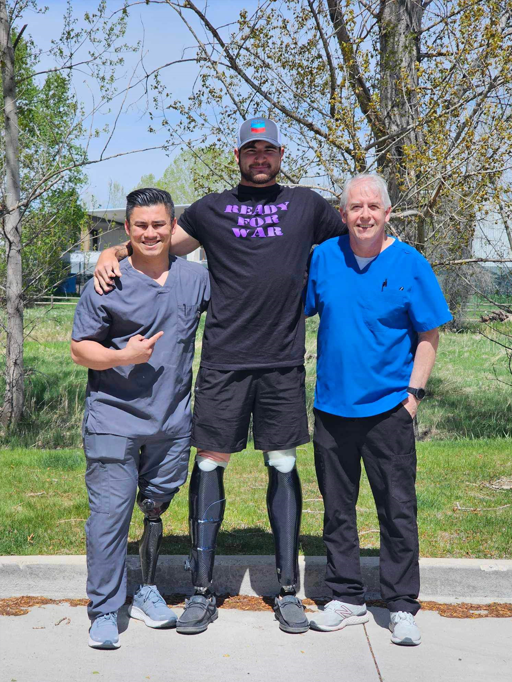 A man with a prosthetic leg is posing for a picture with two other men