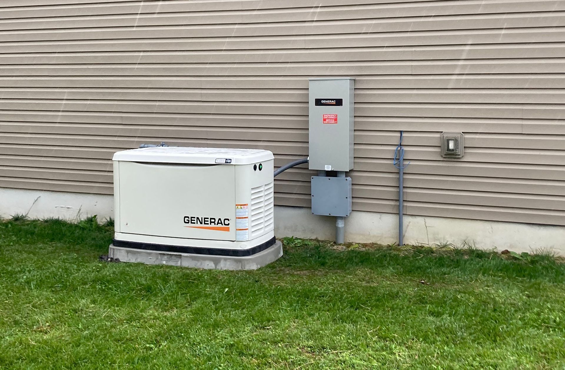 Outdoor GENERAC generator beside a house with utility box and gas meter on the grass