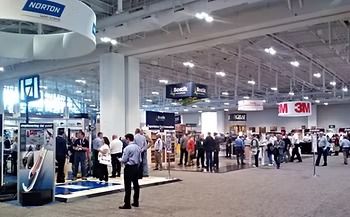 Large trade show floor with attendees; branded booths for Norton, 3M, etc.