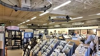 Interior of a tile showroom, with displays of tile samples. The store has a high ceiling and bright lighting.