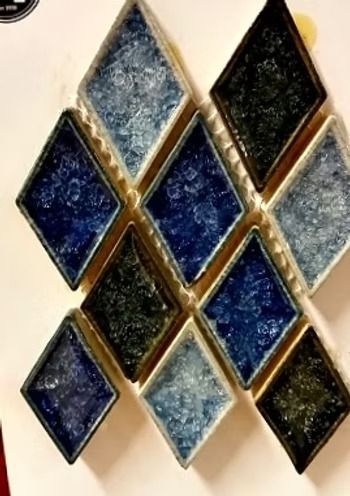 Diamond-shaped mosaic tiles in shades of blue and black, arranged on a white surface.