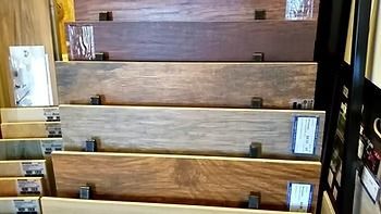 Display of various wood flooring samples, arranged in a stack, showcasing different colors and textures.