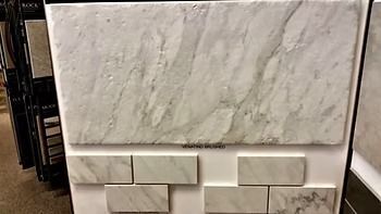 Display board with various white marble tiles, showing different sizes and patterns.