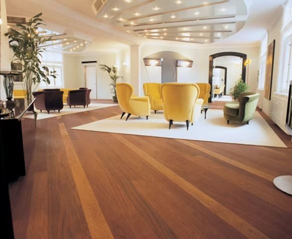 Spacious lobby with hardwood floors and modern furniture: yellow, green, and brown chairs on a white rug.