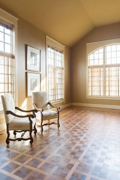 Two cream armchairs sit near windows in a room with wood floors and tan walls.