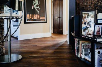 Hardwood floor in a home hallway with art, a doorway, and a bookshelf.