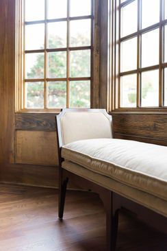 A window seat with a white cushion sits near a wooden window.