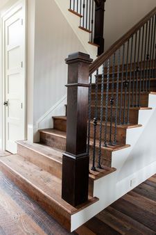Wooden staircase with dark brown railing and posts, leading upwards.