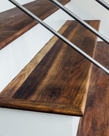 Wooden floating stairs with dark brown treads, white risers, and metal railings.