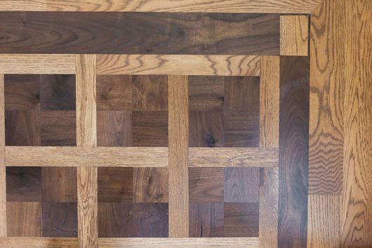 Wooden floor with light and dark brown parquet squares and border.