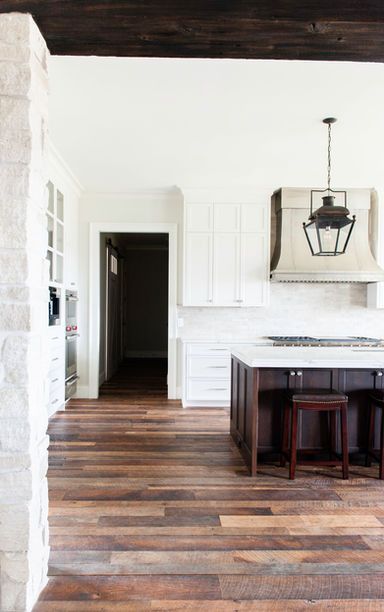 Kitchen with white cabinets, dark island and wood floor.