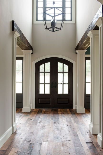 Entryway with arched dark wood double doors, wood floors, and a lantern chandelier.