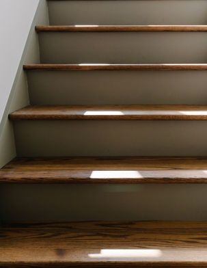 Wooden stairs with sunlight shining on the steps, painted a gray color.