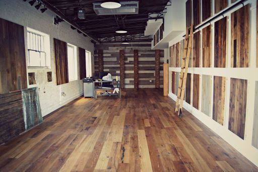 Empty room with wood floors, walls with wood panels, and a ladder leaning against a wall.