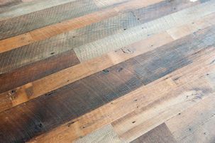 Angled view of reclaimed wood flooring planks in various warm tones.