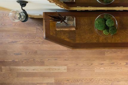 Wooden table with decor, overhead light, and light brown hardwood flooring.