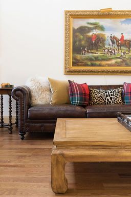 Leather sofa with colorful pillows, wooden coffee table, and painting above.