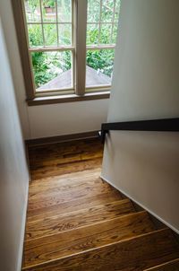 Wooden staircase leading down, near a window overlooking trees.