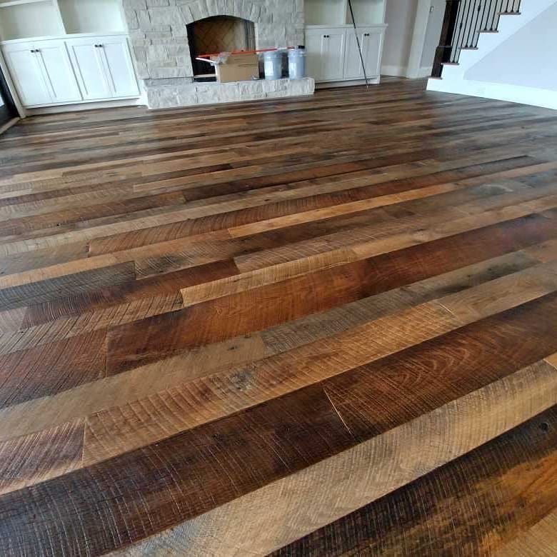 Rustic hardwood floor in a living room, with a fireplace and cabinets in the background.