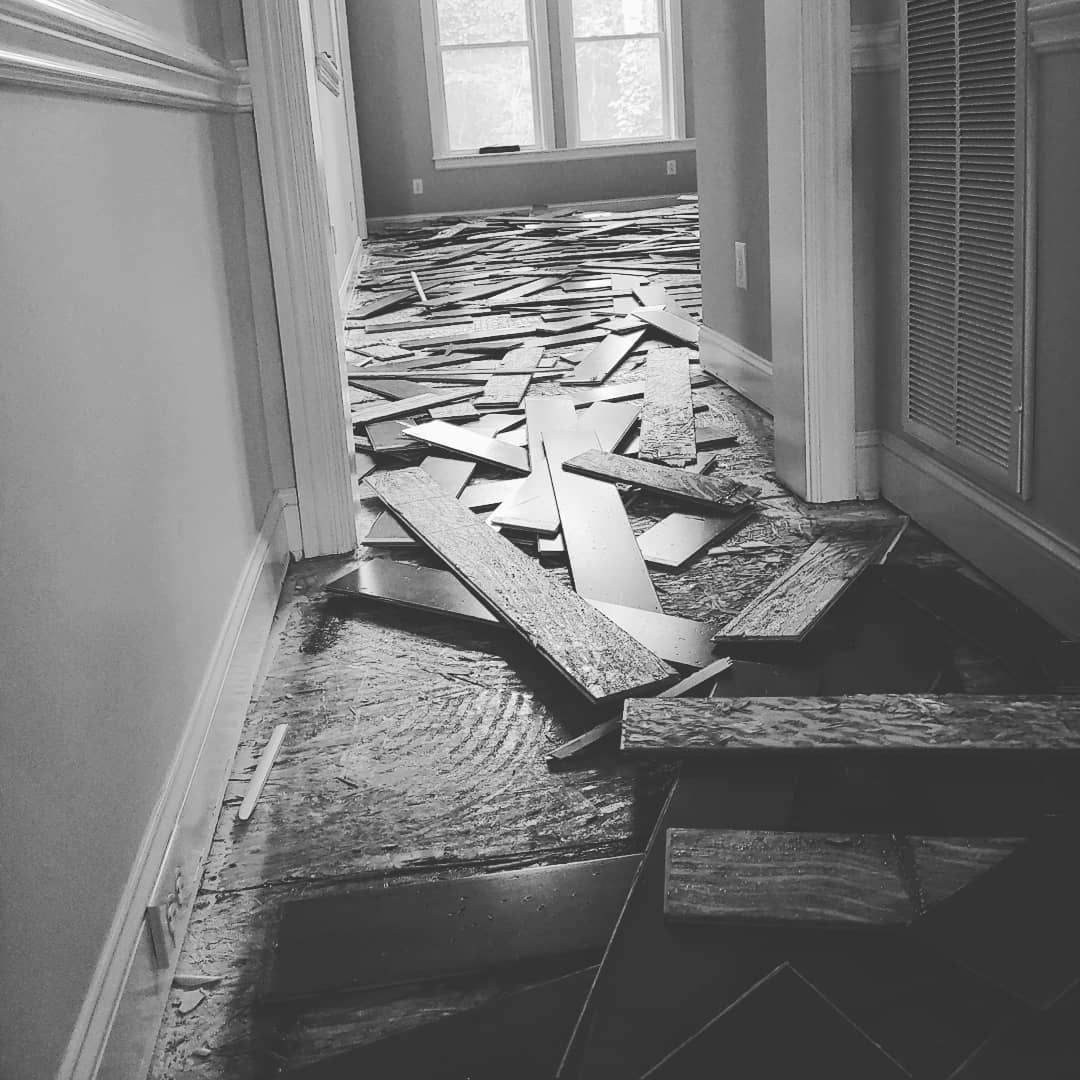 Hallway with debris from floor demolition. Boards and rubble scattered.
